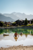Une personne  est assise dans l'eau au bord du lac
